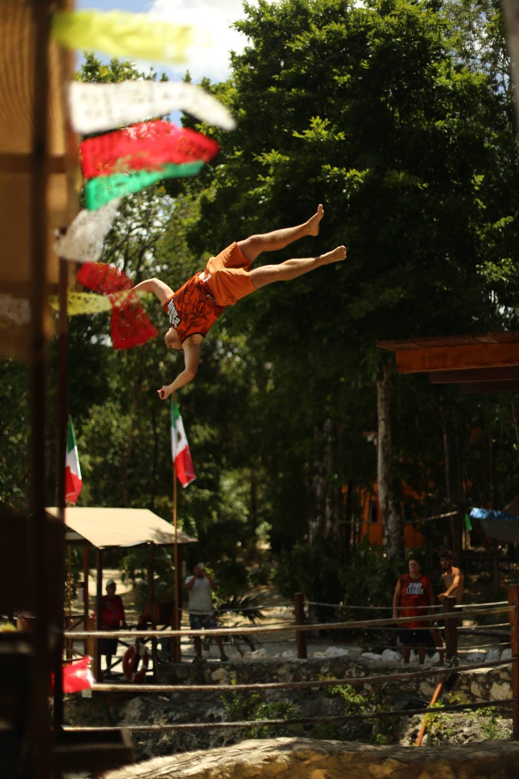 A jumper diving past the Mexican flags from the top of the tower